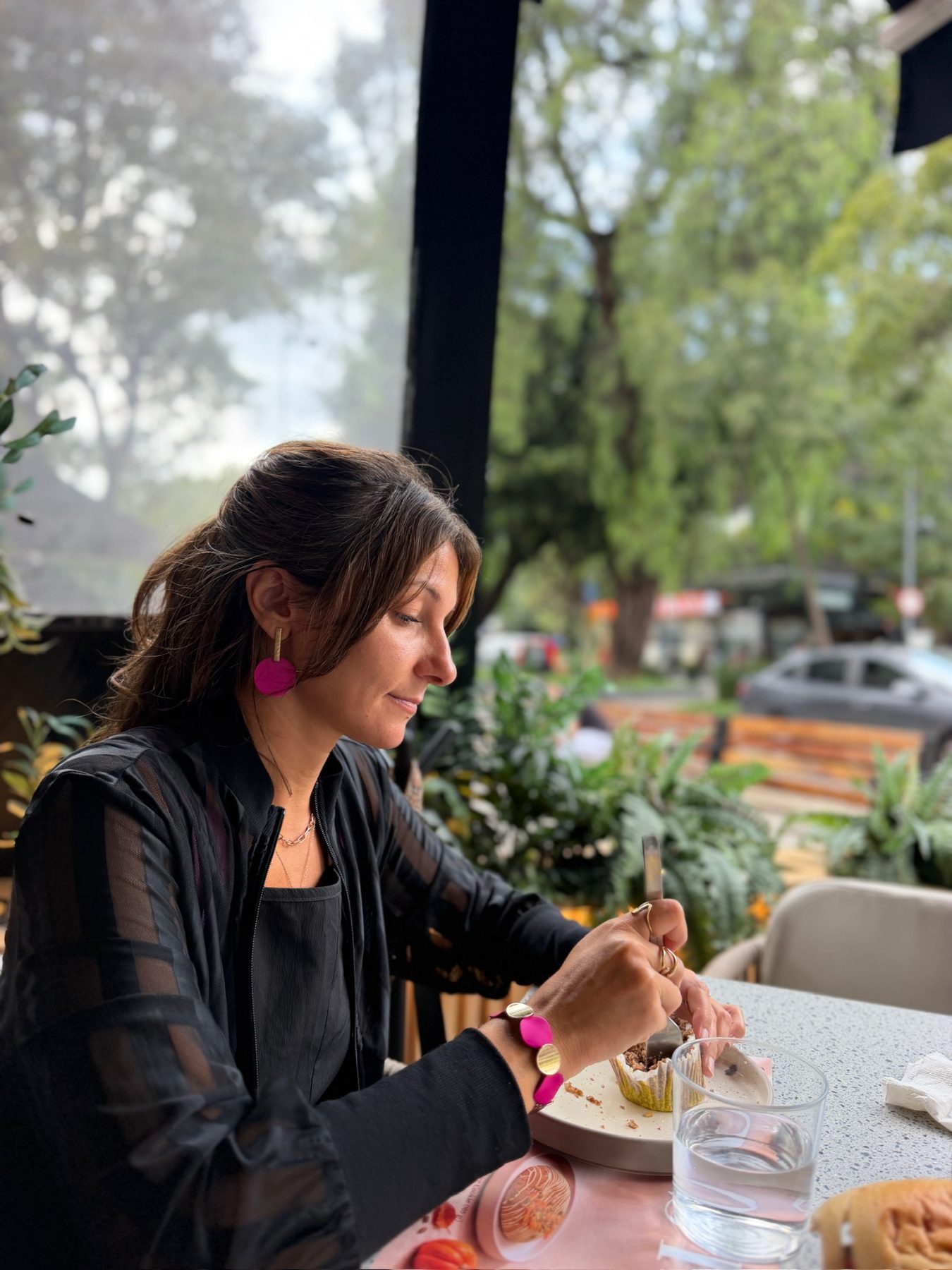 Dalia en noir à la terrasse d'un café en ville, boucles d'oreilles dorées